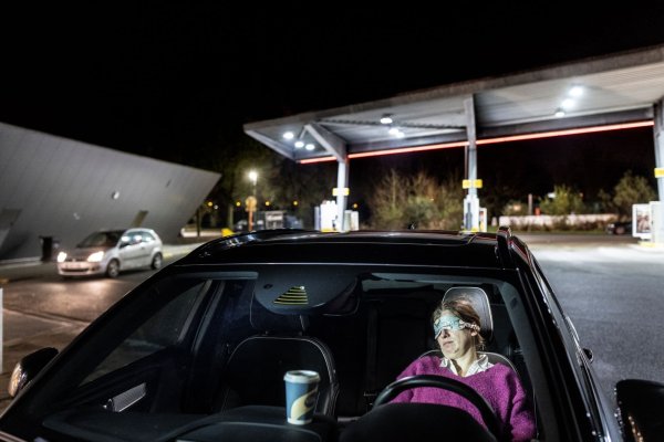 vrouw die powernap doet op parkeerplaats van een tankstation